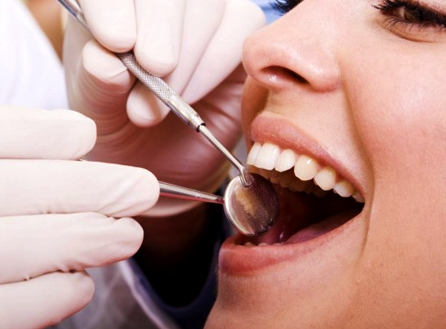 A dentist is looking at female's teeth